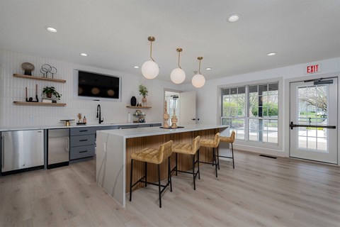 a large kitchen with an island and chairs in front of a door