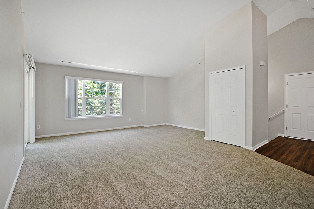 an empty living room with a window and a door