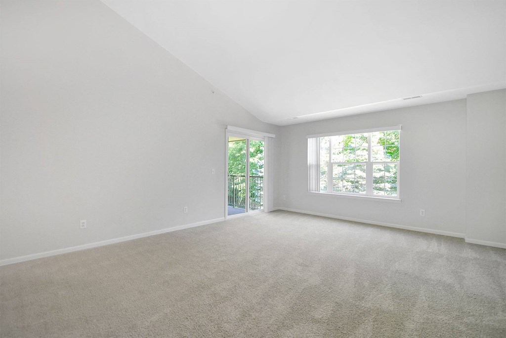 an empty living room with a large window and carpet