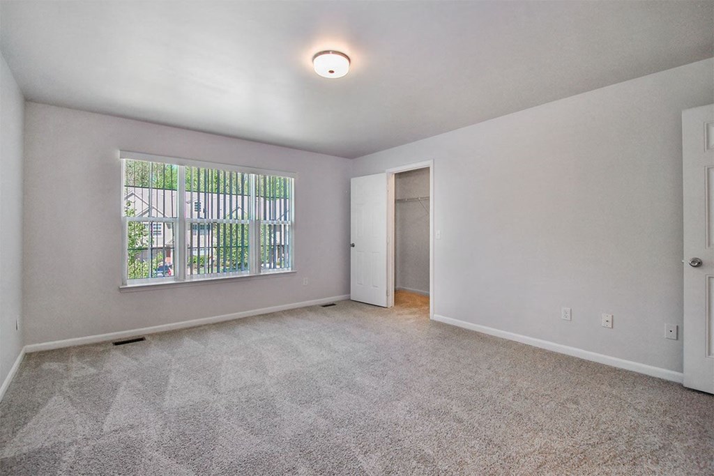 a spacious living room with a large window and carpeting