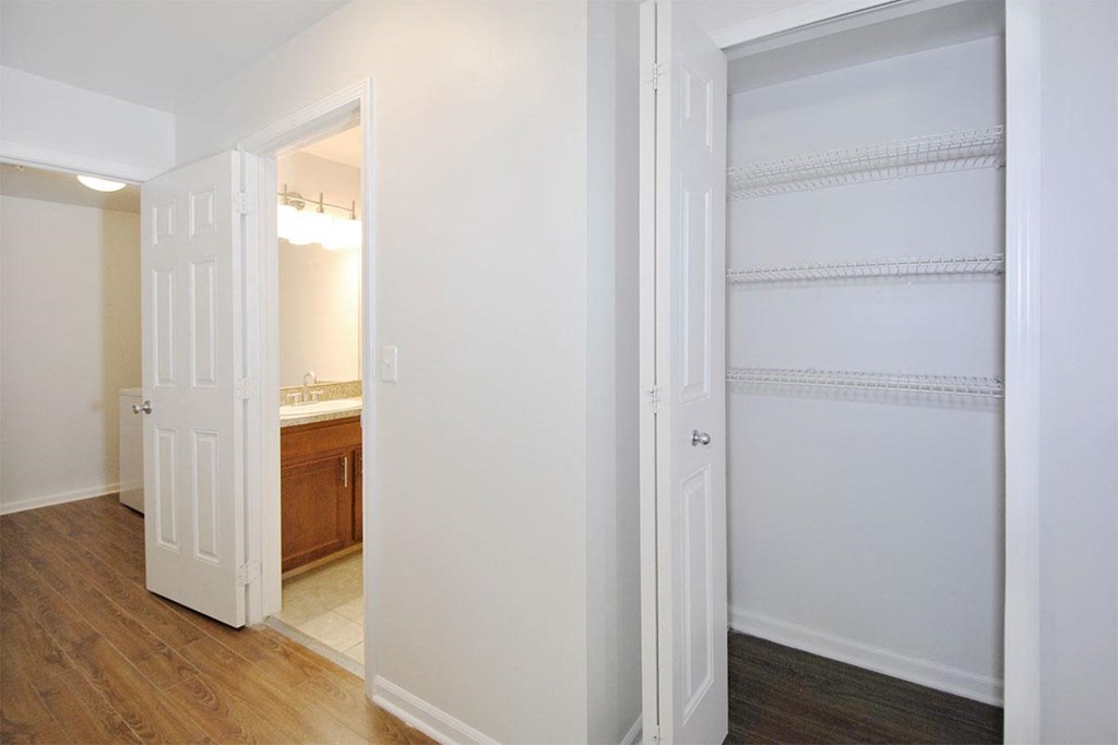 a bedroom with a closet and a bathroom with a mirror