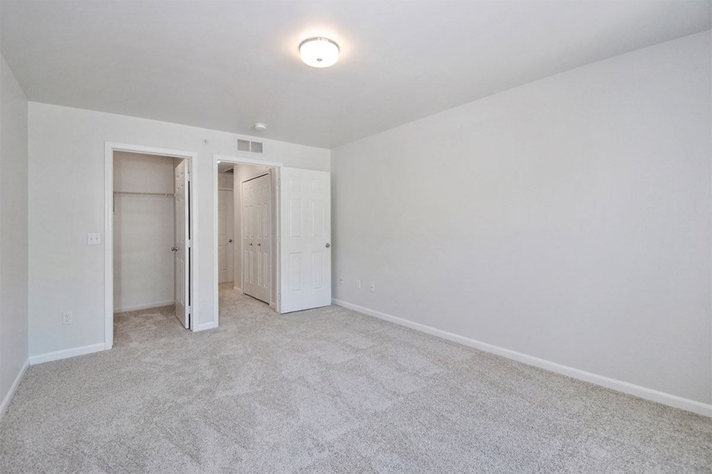 a bedroom with a carpeted floor and a closet