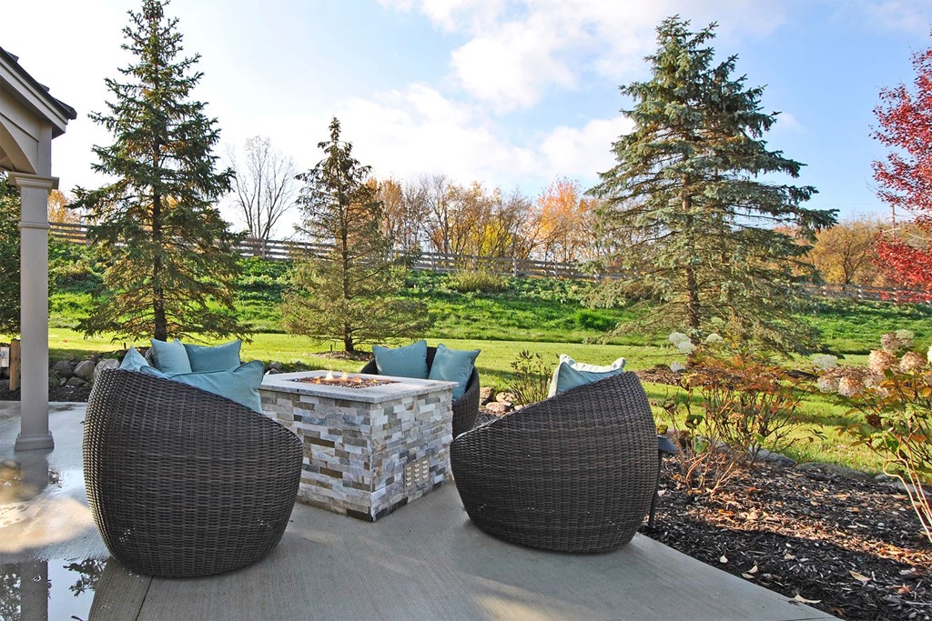 a patio with chairs and a fire pit