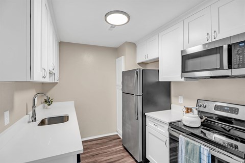 A kitchen with a refrigerator, stove, and microwave.