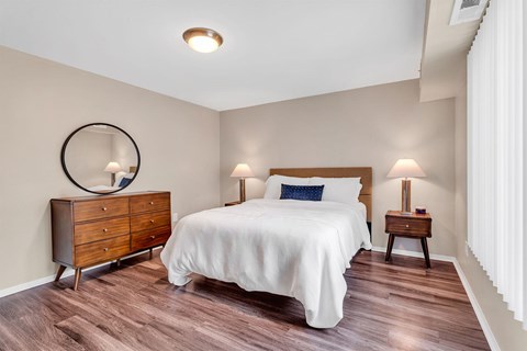 A bedroom with a bed, nightstand, and dresser.