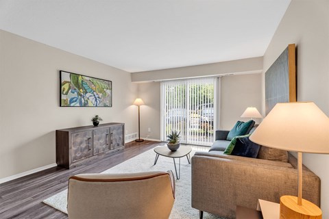A living room with a brown couch, a chair, a lamp, and a painting on the wall.