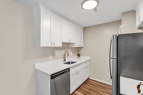 A kitchen with white cabinets and a black refrigerator.