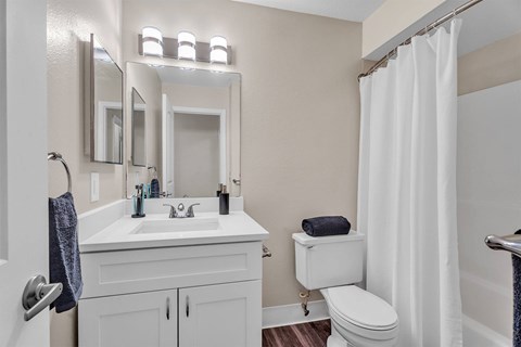 A white bathroom with a toilet, sink, and mirror.