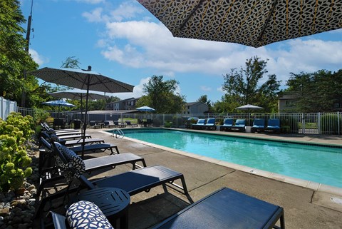A pool area with sun loungers and umbrellas.