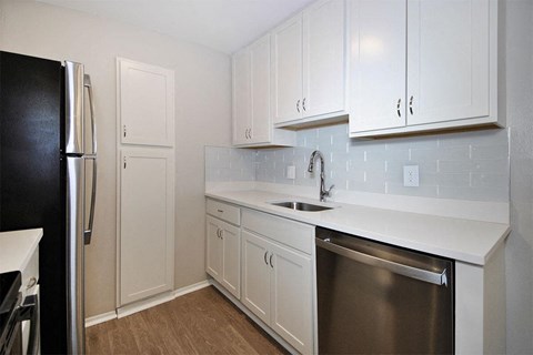 A kitchen with white cabinets and a black refrigerator.