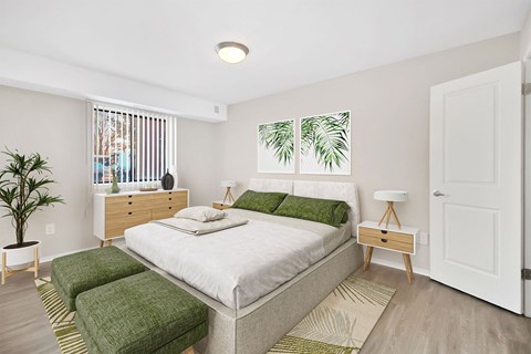 A bedroom with a large bed and a plant.