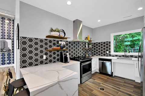 A modern kitchen with a black and white tile backsplash.