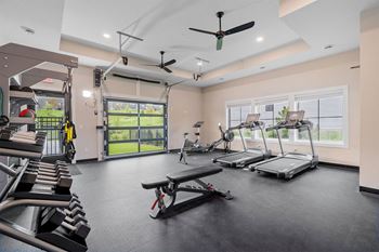 a gym with treadmills and weights and a window