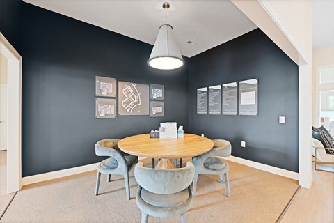 A modern dining room with a round table and grey chairs.