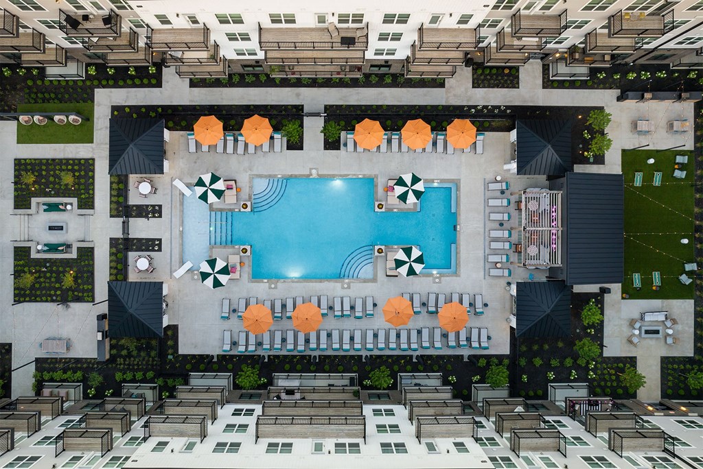 a rendering of the pool area of a hotel with orange umbrellas