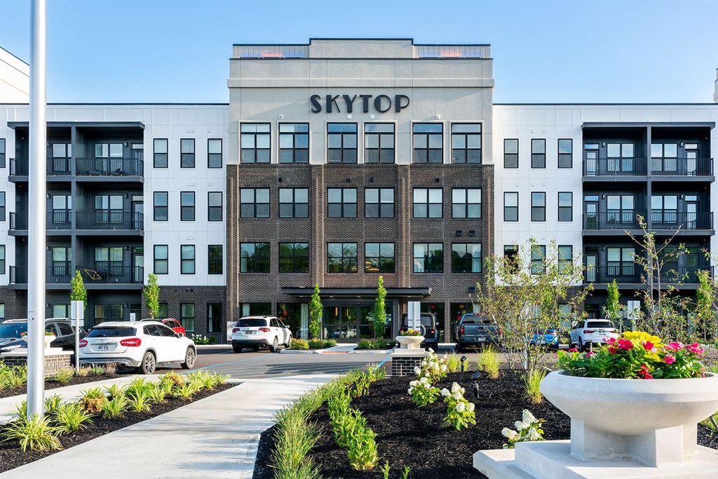 a view of the skytop building from the sidewalk in front of a parking lot