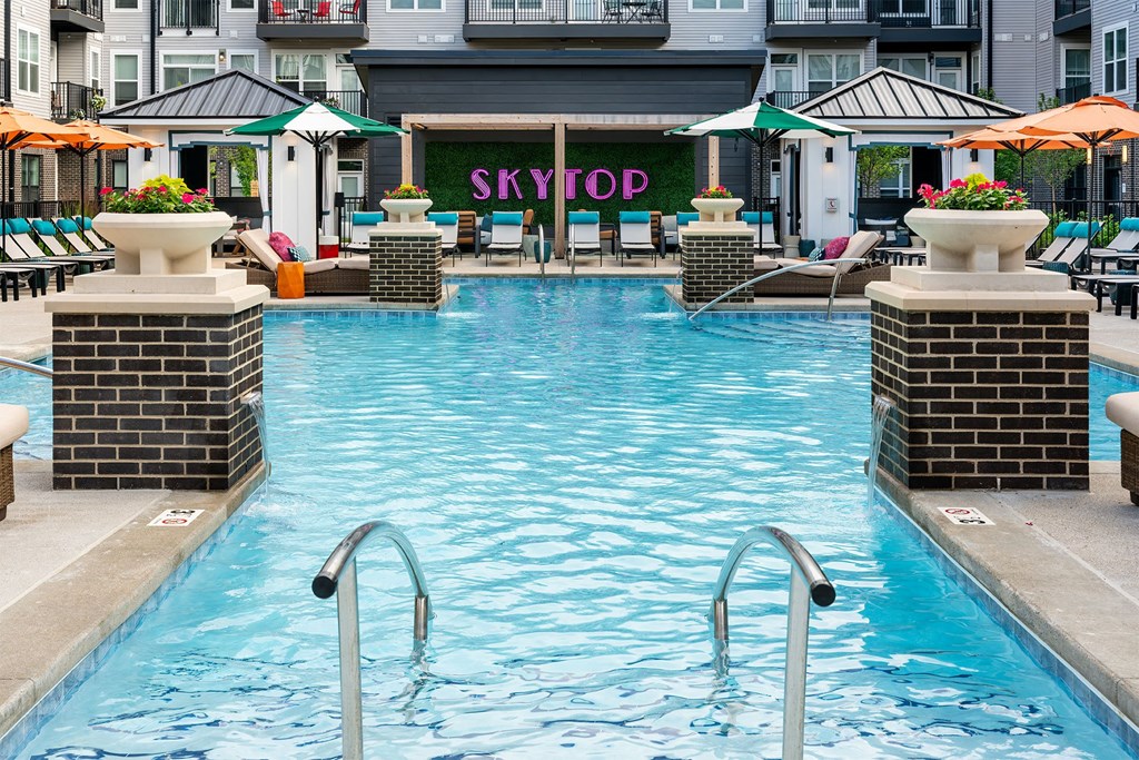 a swimming pool in front of a hotel with umbrellas