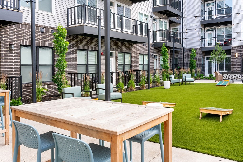a communal area with a table and chairs in front of an apartment building