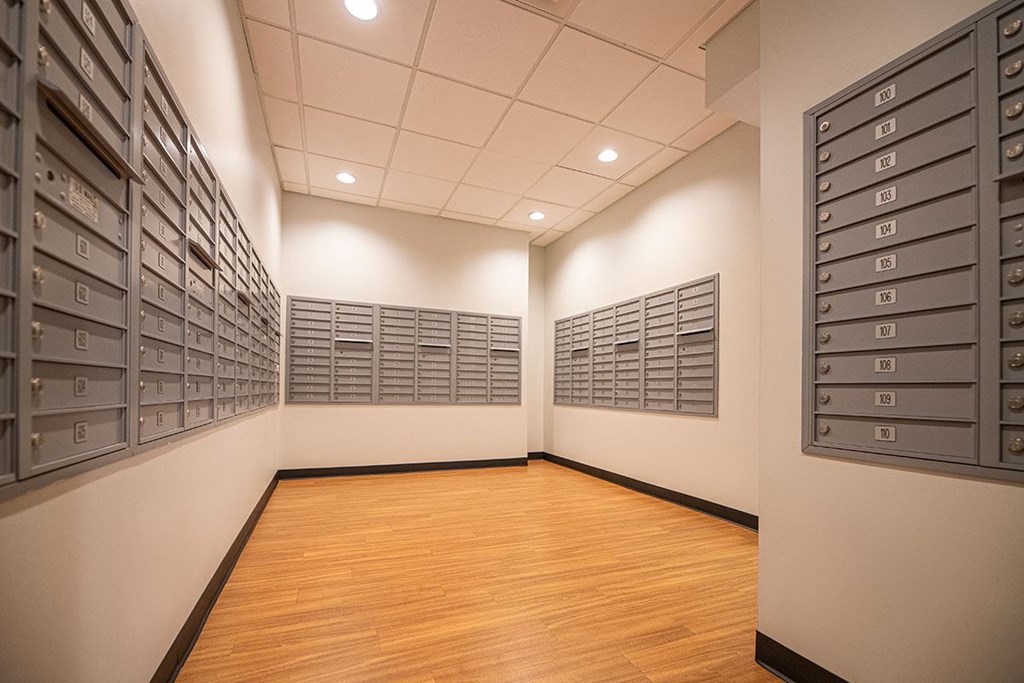 A room with a wooden floor and a wall of mailboxes.