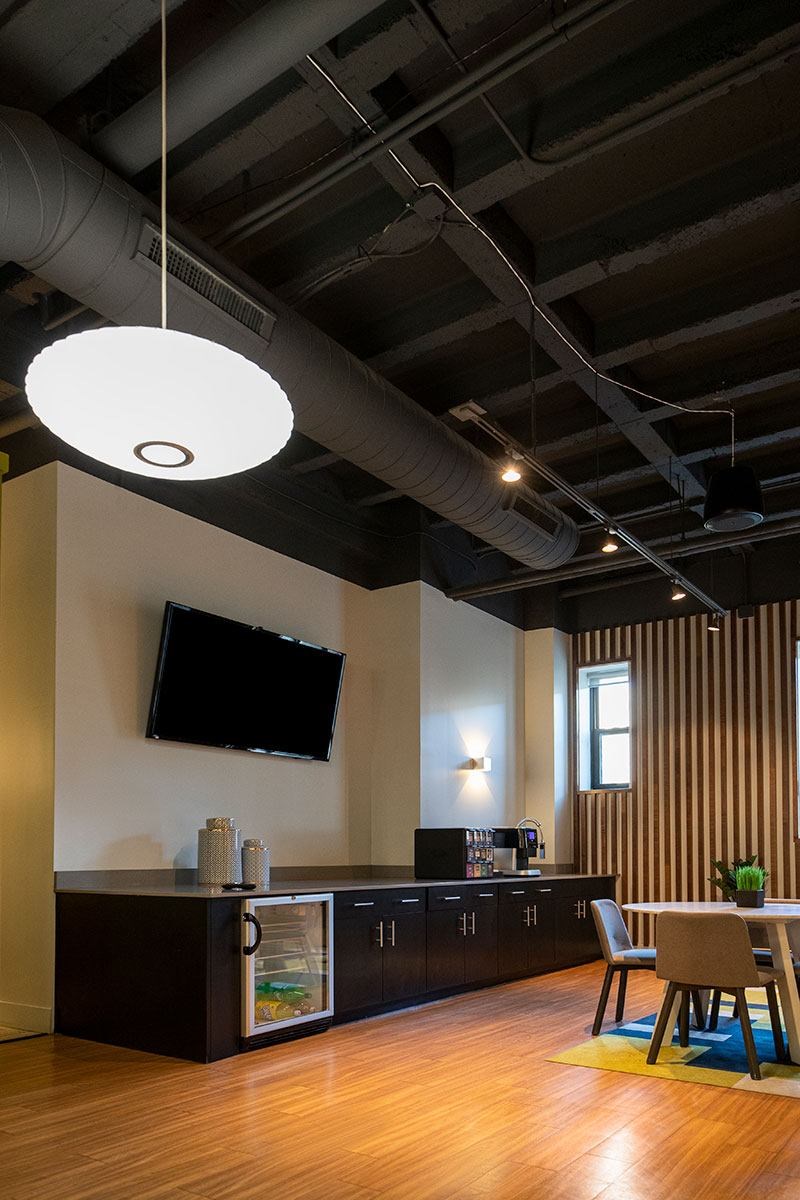 A modern kitchen with a television mounted on the wall and a wooden floor.