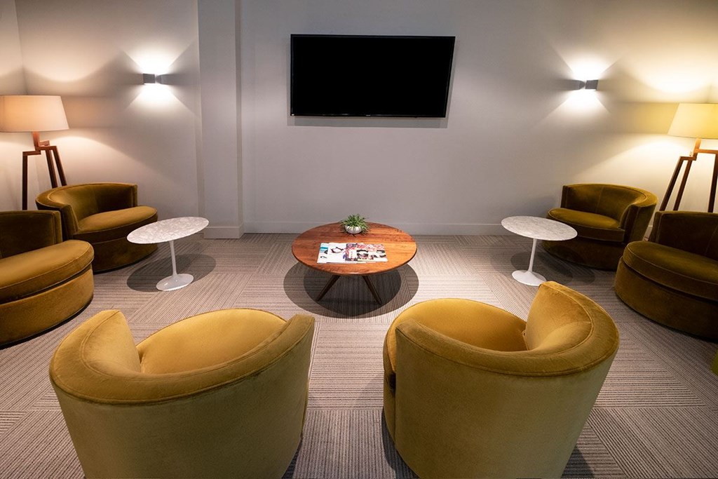 A room with yellow chairs and a table with a plant on it.