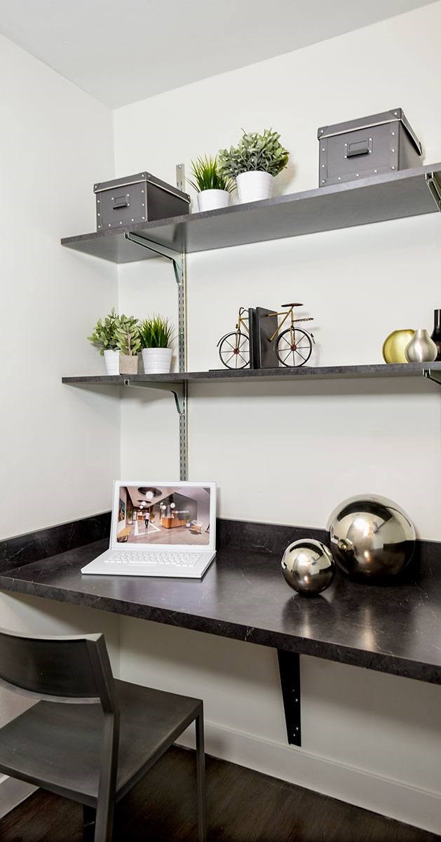 A black desk with a laptop and a picture frame on it.