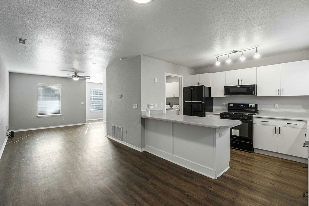 A kitchen with white cabinets and a black countertop.