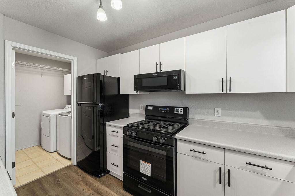 A kitchen with black appliances and white cabinets.