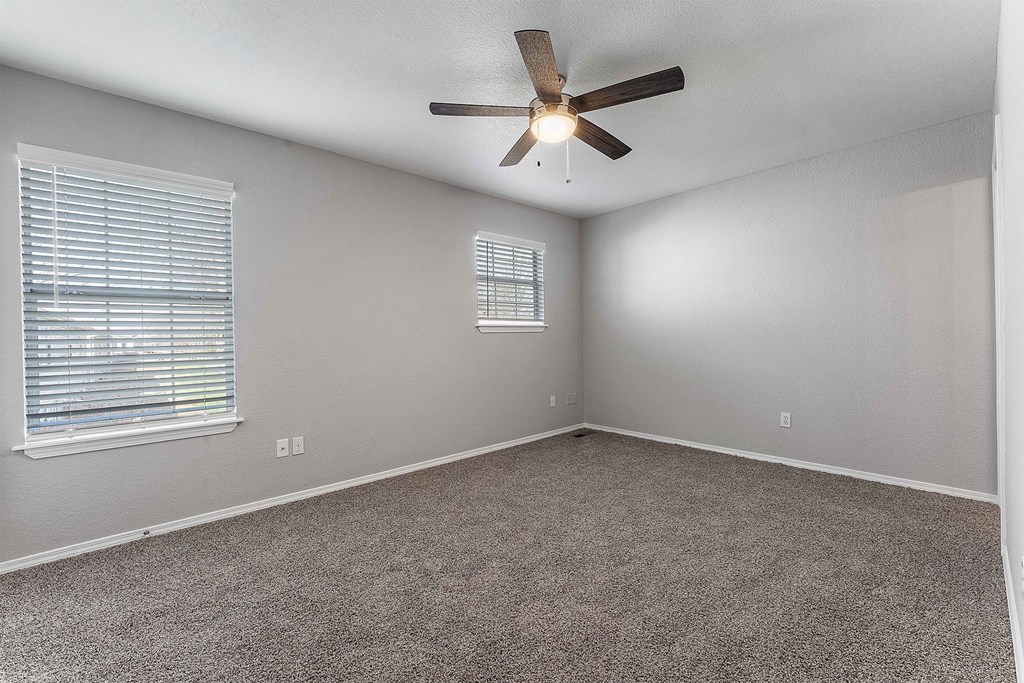 A room with a ceiling fan and carpeted floor.