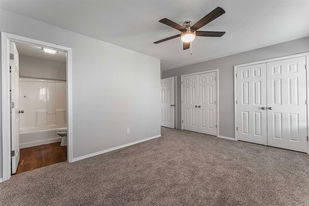 A room with a ceiling fan and three doors.