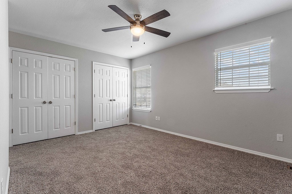 A room with a ceiling fan and two doors.