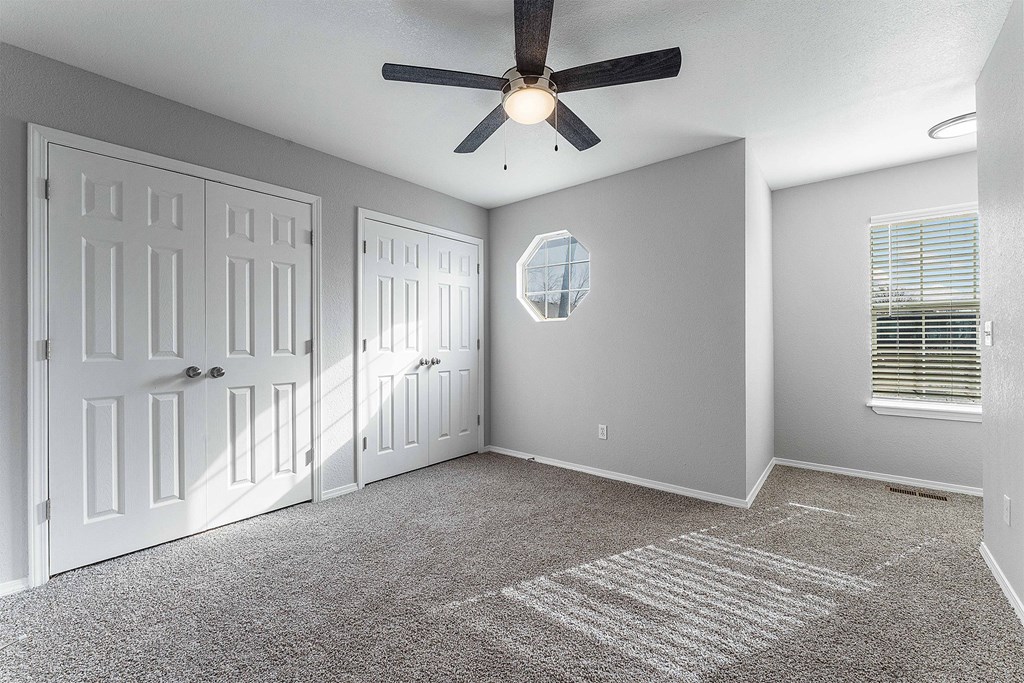 A room with a ceiling fan and a carpeted floor.