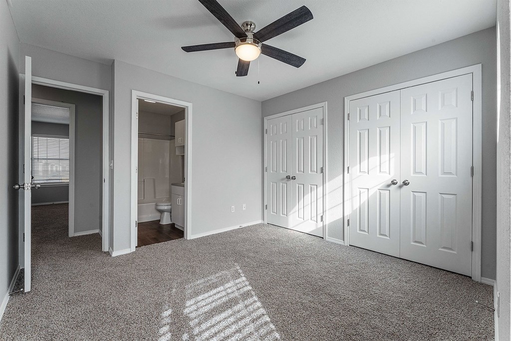 A room with a ceiling fan and three doors.