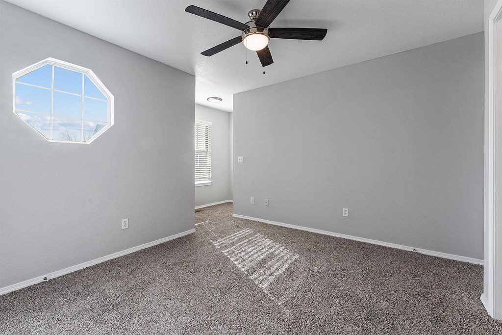A room with a ceiling fan and a hexagonal window.