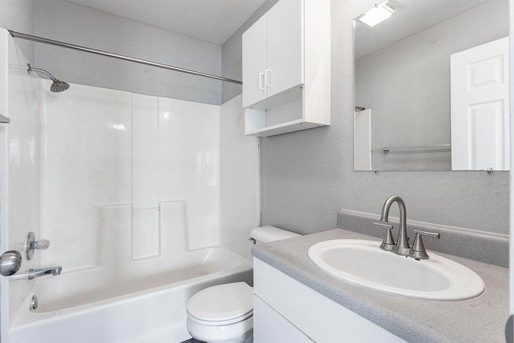 A white bathroom with a toilet, sink, and shower.
