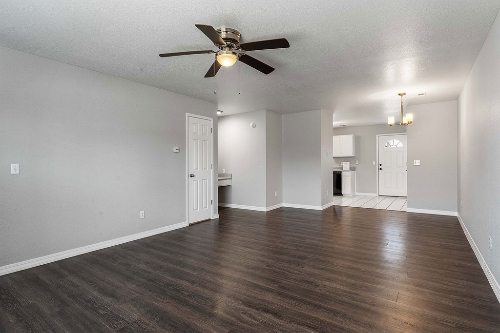 A room with a ceiling fan and wooden flooring.