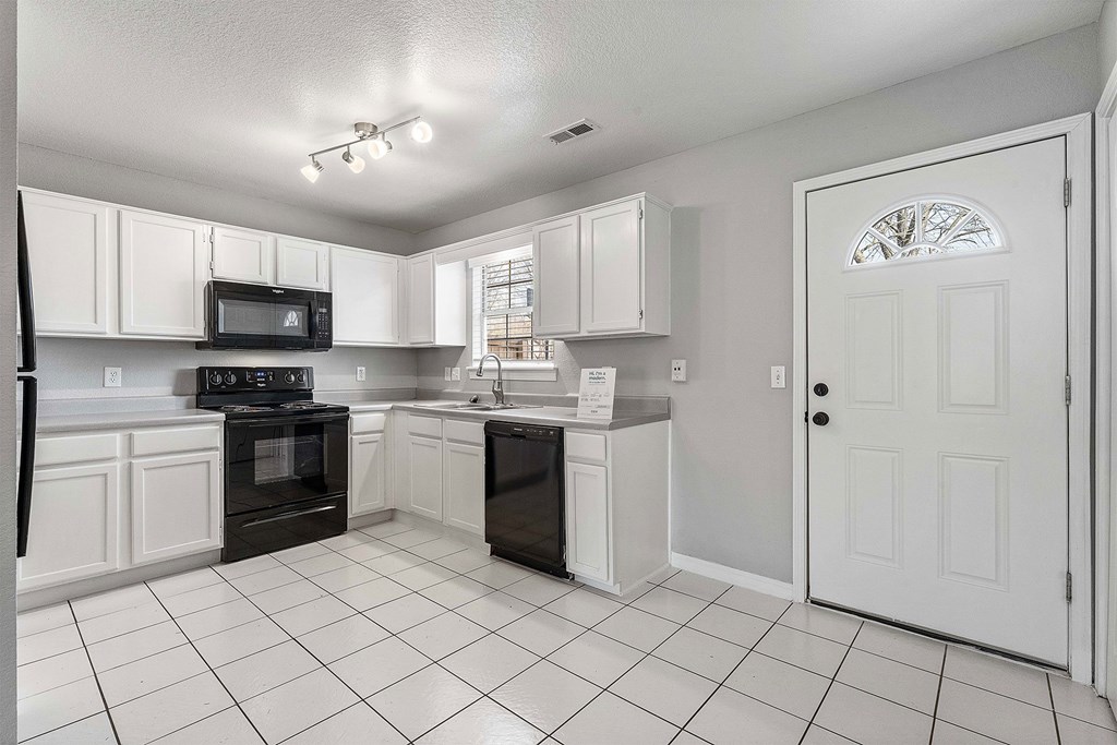 A kitchen with white cabinets and black appliances.