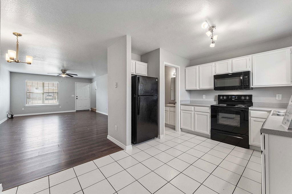 A kitchen with black appliances and white cabinets.