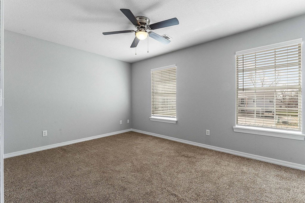 A room with a ceiling fan and carpeted floor.