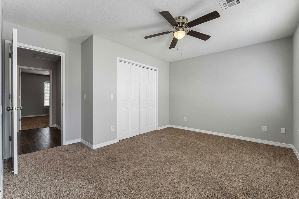 A room with a ceiling fan and carpeted floor.