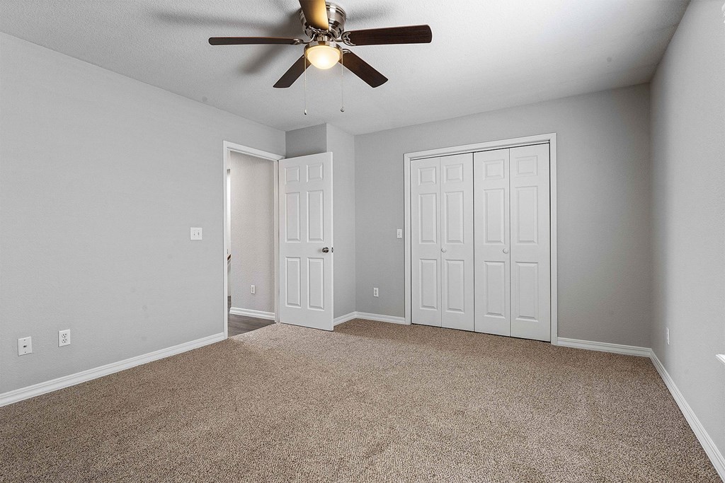 A room with a ceiling fan and two doors.