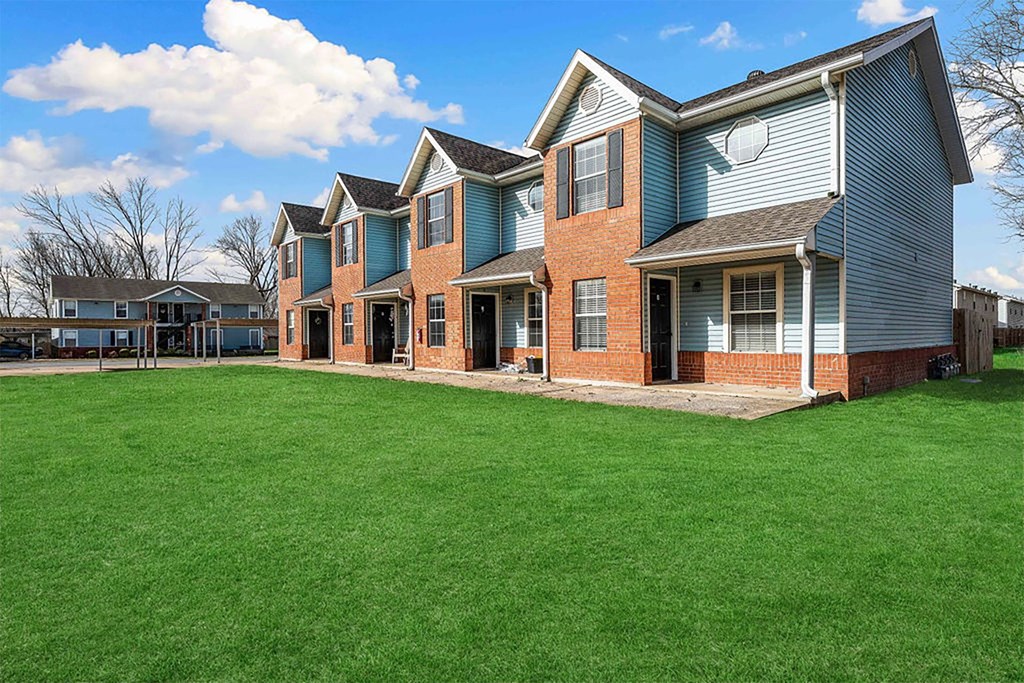 A blue house with a green lawn in front.