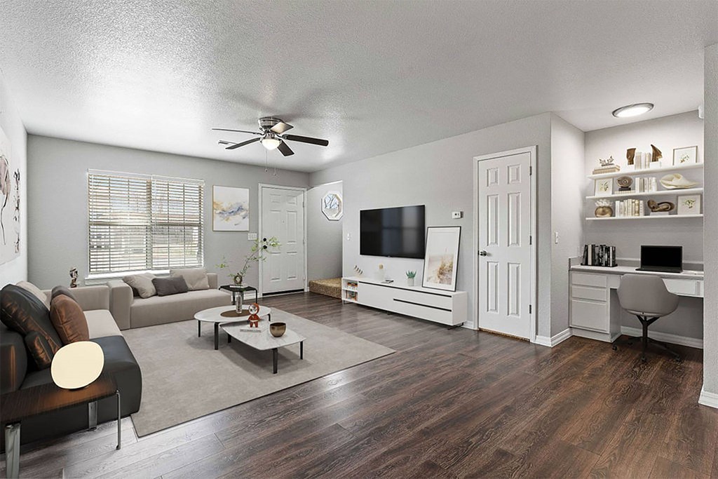 A living room with a couch, a coffee table, a television, and a desk.