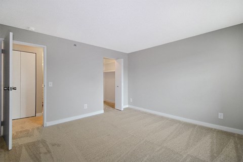 A room with a carpeted floor and a door on the left.