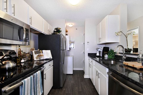 A kitchen with black countertops and white cabinets.