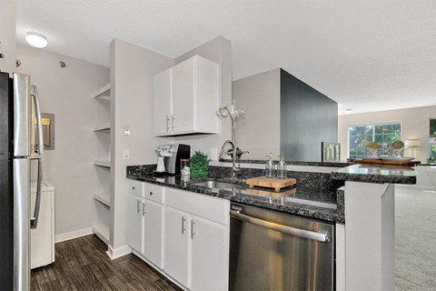 A kitchen with white cabinets and a black countertop.