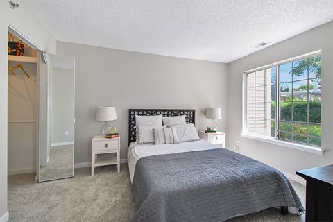 A bedroom with a large bed and a window with blinds.