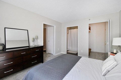 A bedroom with a large bed, a dresser with a mirror, and a lamp.
