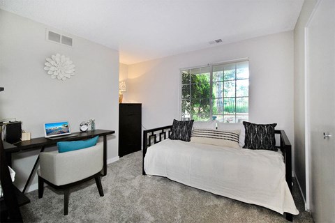 A bedroom with a bed, desk, and chair.