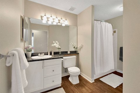 A white toilet sits in a bathroom with a white shower curtain.